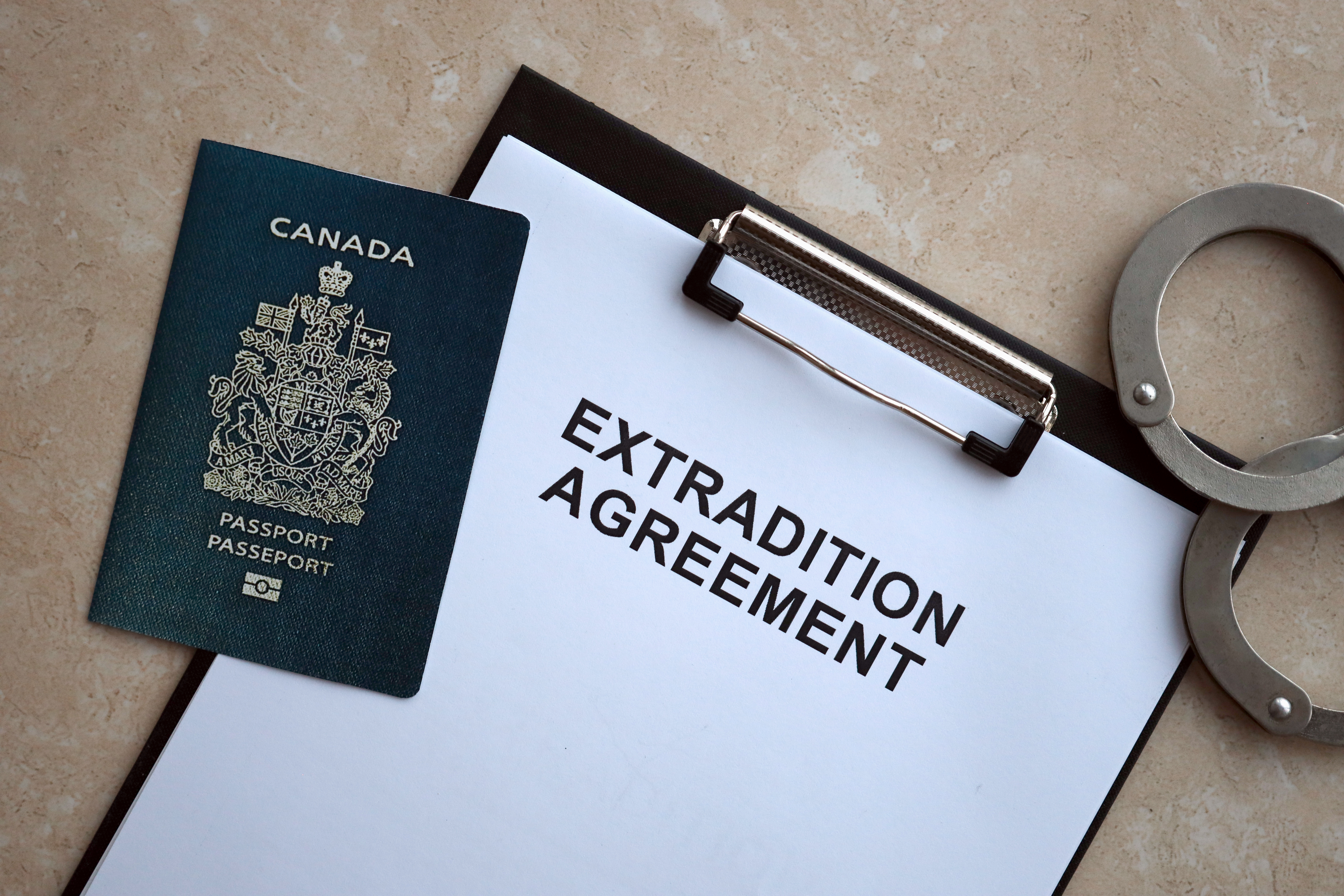 Passport of Canada and Extradition Agreement with handcuffs on table